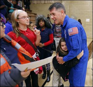 Astronaut Shane Kimbrough gets a hug from kindergartner Mavric Smith as he speaks with fifth-grader Heather Shiffler, left, fifth-grader Jada Callahan, center, and others at Discovery Academy.