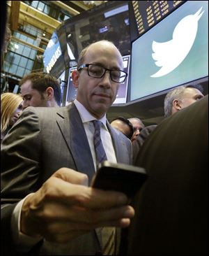 Twitter CEO Dick Costolo, uses his mobile phone as he waits for shares to begin trading during the IPO, on the floor of the New York Stock Exchange. Twitter’s stock opened at $45.10 a share on Thursday, its first day of trading, 73 percent above its initial offering price.