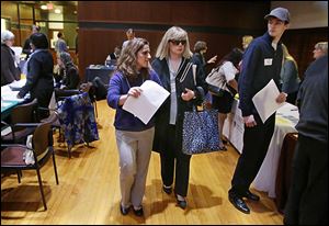 Maura Mazzocca attends a job fair for the visually impaired with the aid of volunteer guide Kate Loosian, left, at Radcliffe Yard in Cambridge, Mass.