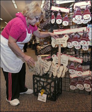 Susan Santana of Walbridge stocks her booth with dog-bone-shaped signs at the Toledo show. She is one of the more than 80 exhibitors. 