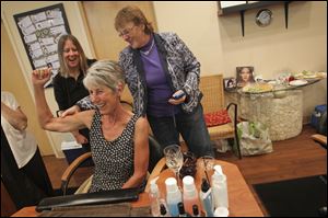 Cheryl McCormick laughs and flexes her arm as her friend Kim Kaseman of Waterville squeezes it, and Mary Ensman of Toledo watches at Soto Spa in Perrysburg.