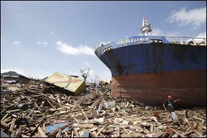 A survivor walks by a large ship that was washed ashore by strong waves caused by Typhoon Haiyan in the Philippines.