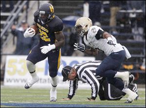 A ref is knocked to the ground as UT's David Fluellen is chased by Navy's Lonnie Richardson during game at the University of Toledo Glass Bowl in Toledo, Ohio.