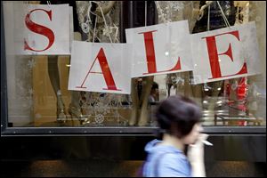 A person passes a retail store with sale sign displayed in the window in Philadelphia.