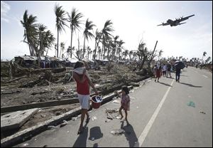 Survivors look up at a military C-130 plane as it arrives at typhoon-ravaged Tacloban city, Leyte province in central Philippines on Monday, Nov. 11, 2013. Haiyan slammed the island nation with a storm surge two stories high and some of the highest winds ever measured in a tropical cyclone.