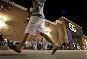 Customers wait in line outside a Best Buy store in Arlington, Texas before midnight on Thanksgiving in 2012. This year the chain’s opening time will advance six hours to 6 p.m.  At least a dozen major retailers are planing to welcome customers on Thanksgiving Day. 