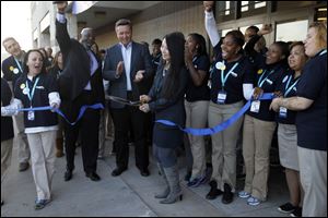 Toledo store manager Jennifer Tucker, center, cuts the ribbon for the store's grand opening, as Gabriel Brothers CEO Ken Seipel, to her left, and Toledo Mayor Mike Bell, with his hand raised, cheer on. 