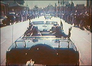 Footage taken by presidential aide Dave Powers and photographed from a television screen shows President John F. Kennedy, accompanied by his wife, Jacqueline, waving to the crowd in Dallas on Nov. 22, 1963. 