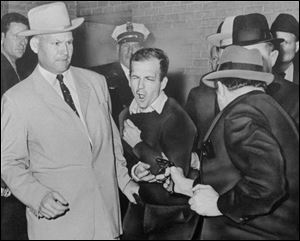 Lee Harvey Oswald, assassin of President John F. Kennedy, reacts as Dallas night club owner Jack Ruby, foreground, shoots him at Dallas police headquarters on Nov. 24, 1963. At left is Detective Jim Leavelle. 