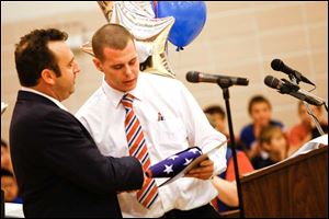 Principal Jeremy Bauer presents Army veteran Sgt. Justin Kuehnle a flag that was flown over the Capitol building in Washington.
