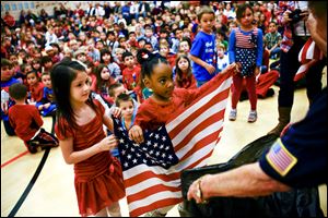 Stranahan Elementary kindergarten students Alivia Kuehnle, 5, left, and Brooklyn Marrows retire their classroom's flag during a Veterans Day assembly.