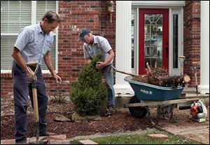 Paul Ewersmann, left, and Jeff Emege, plant a new dwarf alberta spruce in front of the Schneider home in St. Charles, Mo. The family is spending about $5,000 to repair damage done by a tornado.