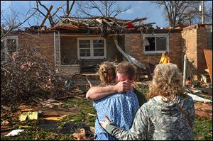 Ray Baughman embraces relatives shortly after a tornado destroyed his home in Pekin, Ill., a city on the Illinois River and south of Peoria. The city sustained significant damage, according to media reports.