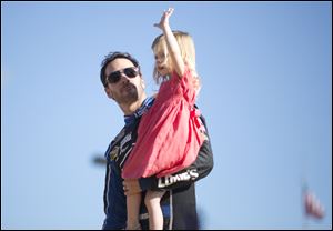 Jimmie Johnson holds his daughter, Genevieve, as they greet fans during driver introductions before the NASCAR Sprint Cub Series race Sunday in Homestead, Fla.