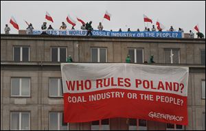Climate activists with protest banners wave polish flags on the rooftop of the Economy Ministry in Warsaw, Poland today. They went up the rooftop to protest a coal conference opening to coincide with U.N. talks on preventing global warming, that is also the result of greenhouse gases coming from burning coal. 