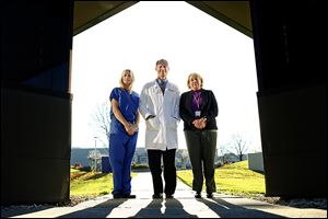 Dr. Christopher Cooper, center, with Holly Burtch, left, and Pamela Brewster stand on the University of Toledo Health Science Campus, the former Medical College of Ohio. His team’s findings were revealed in Dallas at a national meeting of scientists sponsored by the American Heart Association.