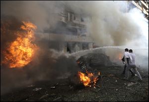 Two Lebanese men react in front of burned cars, at the scene where two explosions have struck near the Iranian Embassy killing many, in Beirut, Lebanon, today.