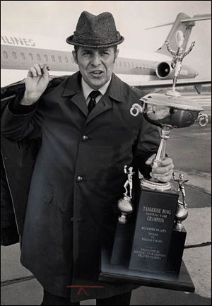 University of Toledo football coach Frank Lauterbur shows off the Tangerine Bowl trophy as he deplanes December 30, 1970, in Toledo on arrival after the game.  