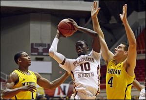 Florida State forward Okaro White, center, goes to the basket against Michigan’s Glenn Robinson, left, and Mitch McGary during a NCAA college basketball game in San Juan, Puerto Rico, today.