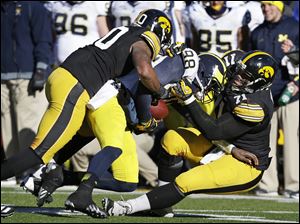 Michigan quarterback Devin Gardner (98) is sacked by Iowa defenders Christian Kirksey, left, and Carl Davis, right, during the second half, Saturday.