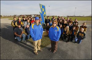 Ida High School track coaches Mike Bolster and Connie DuCharme join their student athletes at the school’s old cinder track. The quarter-mile track will be replaced with a synthetic rubberized surface that will enclose the football field and should be complete by the autumn of 2014.