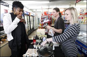Above, Denise Clark tries homemade apple sauce offered by Stephanie Baltes, right, and Judith Hancock, center, registered dietitians with the Toledo-Lucas County Health Department,  during a kickoff event at a Stop & Go convenience store to highlight healthful food choices.
