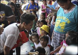 Grammy-winning singer Alicia Keys, left, smiles at a typhoon survivor as she visits the Villamor Air Base in suburban Pasay, south of Manila, Philippines today.