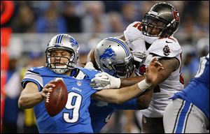 Tampa Bay’s Jonathan Casillas, right, grabs ahold of Matthew Stafford during the fourth quarter on Sunday. The Buccaneers harassed Stafford all day, forcing four interceptions.