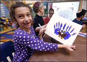 Second-grader Rozie Aronov, 7, holds up a menurkey, a paper-and-paint mashup of a menorah and turkey she created at Hillel Day School in Farmington Hills, Mich., Wednesday. The recent class project reflects one way for Jews in the United States to deal with a rare quirk of the calendar that overlaps Thanksgiving with the start of Hanukkah.