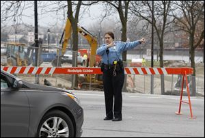 Toledo police officer Theresa Talton directs traffic at the intersection of Summit Street and Jefferson Avenue in downtown Toledo Tuesday, after the roads were closed due to a ruptured natural gas line in Promendade Park.