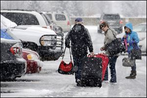 Holiday travelers make their way to their car after arriving at Pittsburgh International Airport in Imperial, Pa. A huge winter storm is expected to have nationwide impact as it causes delays at East Coast airports. 