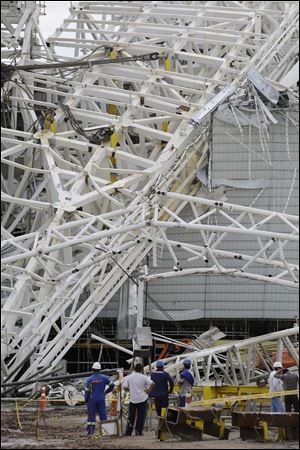 People stand near a metal structure that buckled on part of the Itaquerao Stadium in Sao Paulo, Brazil, Wednesday, Nov. 27, 2013. Part of the stadium that will host the 2014 World Cup opener in Brazil collapsed on Wednesday, causing significant damage and killing three people, authorities said. (AP Photo/Nelson Antoine)