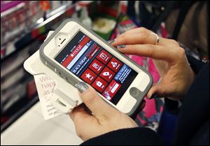 Tashalee Rodriguez, of Boston, uses a smart phone app while shopping at Macy's in downtown Boston.