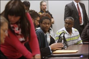 Emmanuell Quinn, center, speaks with his lawyer while seated near his parents in Lucas County juvenile court in October.