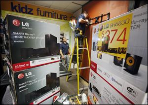 Shawn Manion, on ladder, and Jerry Butte install a Black Friday display Wednesday at the Appliance Center in Maumee.