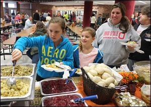 Emilee Gibson, 10, left, her sister Karlee Gibson, 8, mother, Chassity Gibson, and grandmother Rita King, help themselves to Thanksgiving dinner at Willard High School. CSX hired a Columbus catering firm, Concessions by Cox, to make the meal.