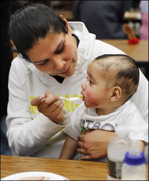 Melissa Rodriguez feeds her 9-month-old son, Abraham Aguilar, at a Thanksgiving dinner at Willard High School.