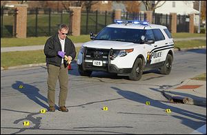 Toledo Detective Terry Cousino picks up shell casings at Page Street and Mayville Place after the shooting outside Moody Manor.