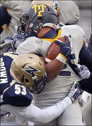 Akron's C.J. Mizell, behind, and Jatavis Brown, left, take down Toledo’s Kennedy Frazier during the fourth quarter. The Rockets amassed just 388 total yards.