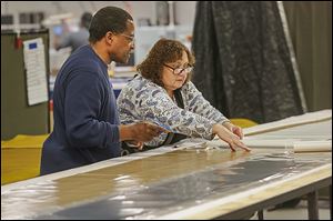 Jim Fisher and Pam Reynolds assemble solar panel components for production at the Toledo-based Xunlight’s manufacturing facility. Xunlight is overhauling its manufacturing process to meet its customers’ demands.