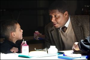 Behavior coach Deonte Moss visits with kindergartner Vincente Diaz, 5, during lunch in the cafeteria at Leverette School in North Toledo. Mr. Moss works with children to help them make good choices and reinforce good behavior.