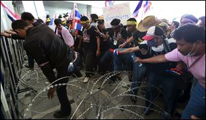Anti-government protesters try to remove barbed wire during a rally in front of the Department of Special Investigation in Bangkok, Thailand.