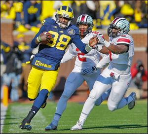 Ohio State linebacker Ryan Shazier (2) and defensive lineman Noah Spence chase Michigan quarterback Devin Gardner. Gardner threw for 451 yards and four touchdowns against the Buckeyes.