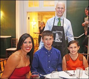 Joe Nugent, sports anchor/reporter at WTVG-TV, Channel 13, standing, waits on Margarita Beale, seated at left, and her children Timothy, 14, and Caroline, 11, at the Family and Child Abuse Prevention Center's Celebrity Wait NIght.