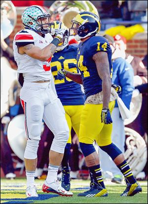 Ohio State receiver Devin Smith quiets the crowd after scoring a touchdown in front of Michigan’s player Josh Furman.