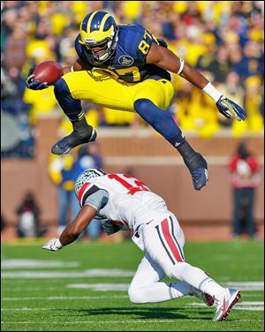 Michigan’s Devin Funchess leaps over Ohio State’s Doran Grant in the second quarter. Funchess scored one of four UM passing TDs.