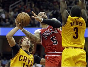 Chicago Bulls' Carlos Boozer (5) shoots against Cleveland Cavaliers' Anderson Varejao, left, of Brazil, and Dion Waiters (3) in the first quarter of an NBA basketball game Saturday.