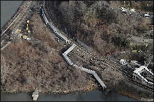 A Metro-North passenger train lays on it's side after derailing in the Bronx borough of New York, today. The train derailed on a curved section of track, coming to rest just inches from the water and causing multiple fatalities and dozens of injuries.