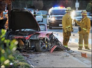 Sheriff's deputies work near the wreckage of a Porsche that crashed into a light pole on Hercules Street near Kelly Johnson Parkway in Valencia, Calif., on Saturday.