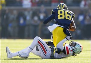 Ohio State’s Bradley Roby wraps up Michigan’s Jehu Chesson during the third quarter on Saturday in Ann Arbor. The Buckeyes’ defense surrendered 603 yards, including 451 passing yards.